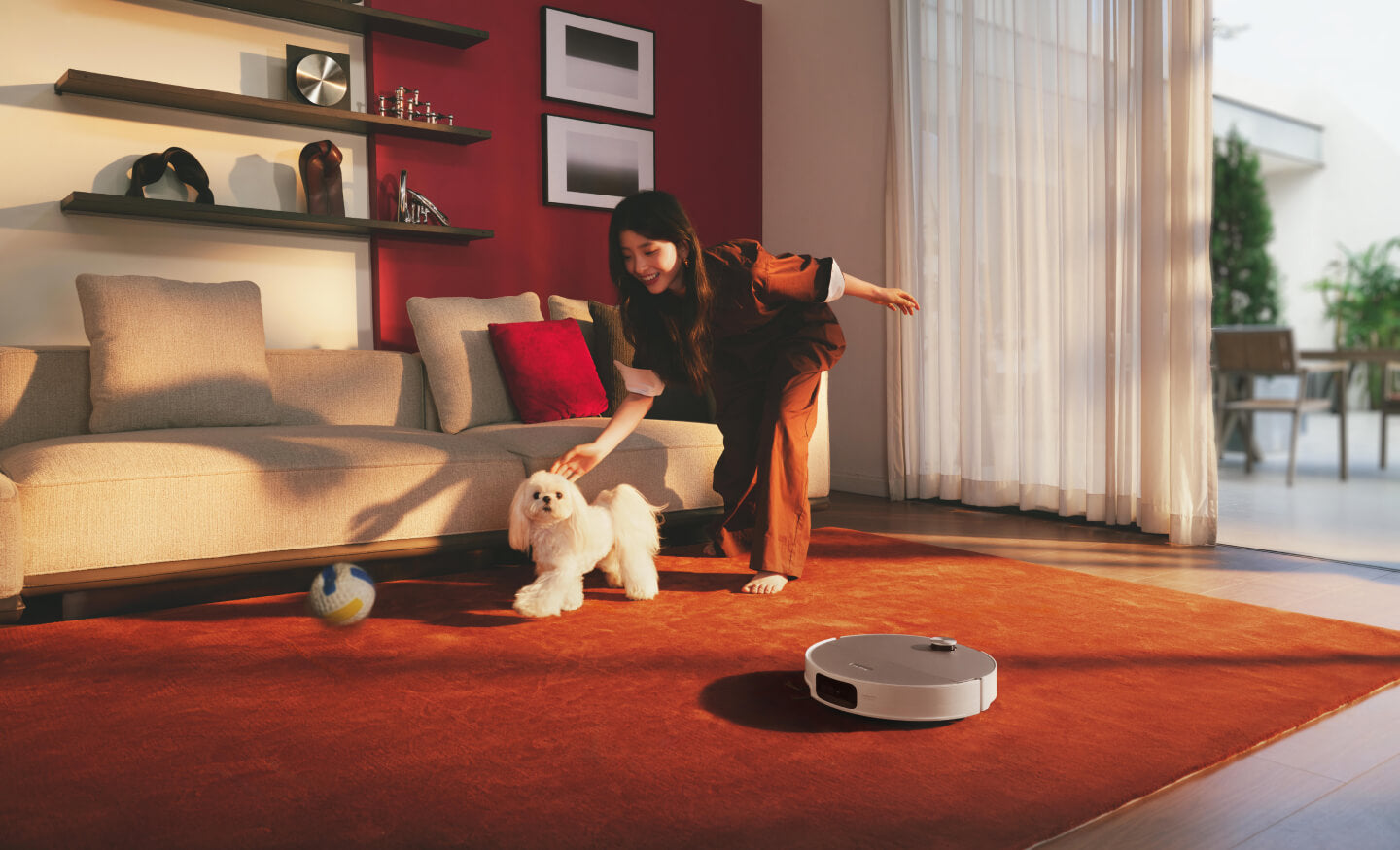 Roborock S10 MaxV Ultra Steam blanc sur un tapis rouge dans un salon, avec une personne et un petit chien sur le visuel promotionnel officiel.